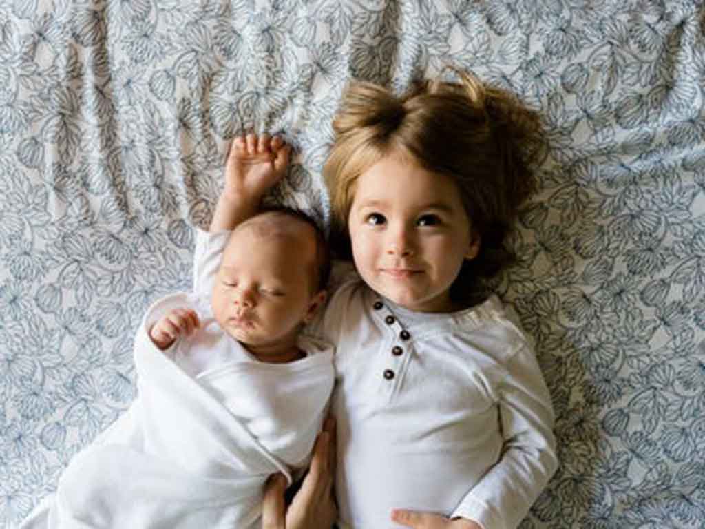 Das Bild zeigt ein Baby und ein zweijähriges Mädchen also Geschwister als Vorschau für den Eltern-Workshop Geschwisterliebe - Geschwisterzoff.