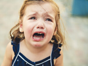 Das Bild zeigt ein trotziges, weinendes dreijähriges Mädchen und dient als Beitragsbild zum Vortrag Gelassen durch die Trotzphase über Kindererziehung von Potsdam bewegt Bildung.